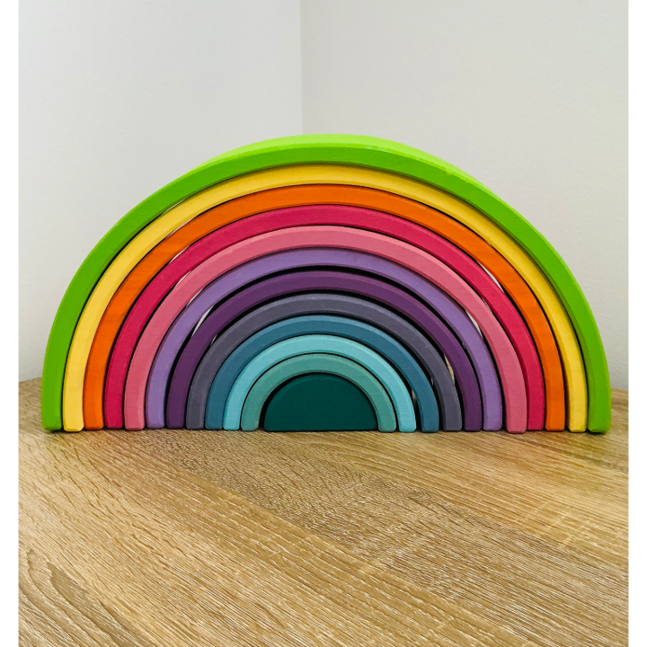 Colorful wooden rainbow toy on a wooden surface 
