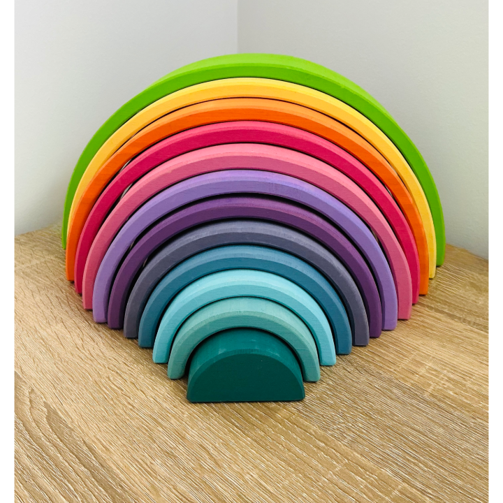 Set of colorful wooden rings stacked in a rainbow pattern on a wooden surface.
